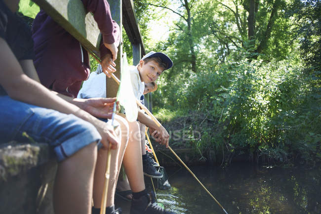 Niños sentados en el puente y pescando - foto de stock