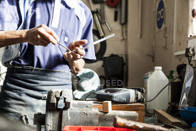 Mid section of young man using screwdriver in repair workshop — Stock Photo