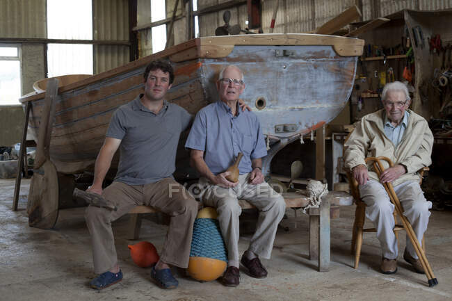 Group portrait of three generations of male boat builders — стоковое фото