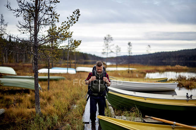 Caminhante caminhando por lago com barcos, Kesankijarvi, Lapônia, Finlândia — Fotografia de Stock