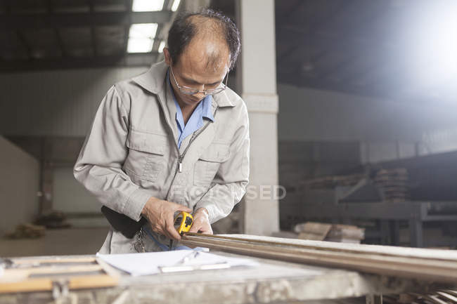Carpentiere che misura assi di legno con metro a nastro in fabbrica, Jiangsu, Cina — Foto stock