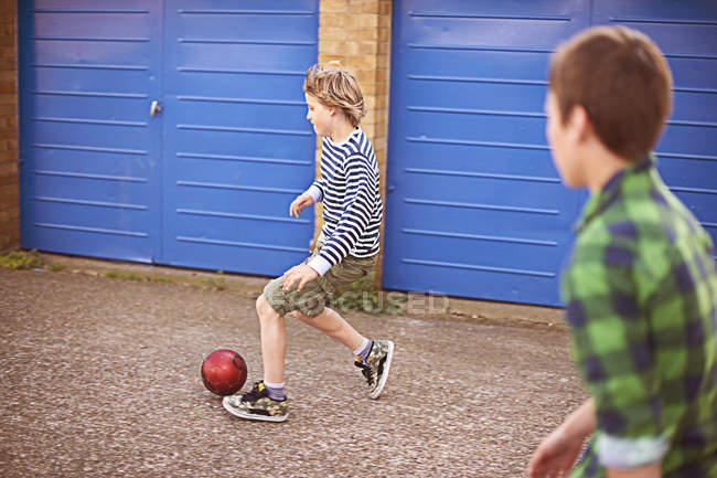 Dos chicos jugando al fútbol en el garaje puertas azules - foto de stock