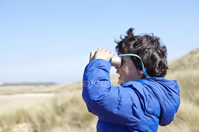 Jovem na praia, olhando através de binóculos de fingir — Fotografia de Stock