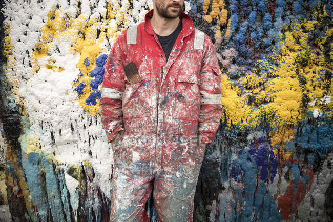 Mid section of male ship painter in front of paint splattered wall in ship painters yard — Stock Photo