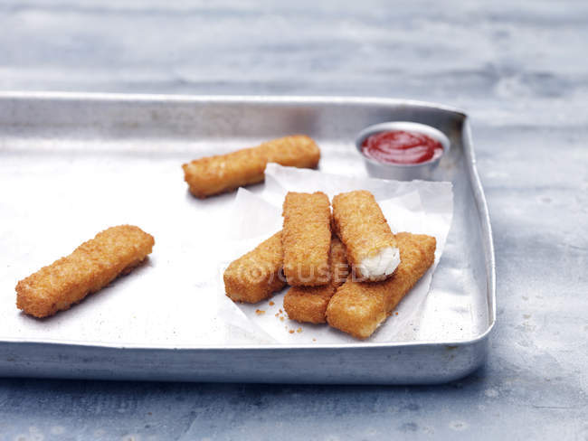 Baking tin with fried chunky cod breaded fish fingers with tomato ketchup — Stock Photo