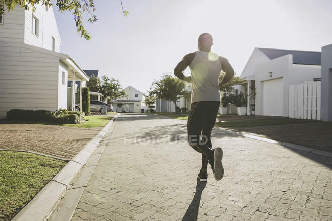 Rear view of man jogging in residential area — Stock Photo