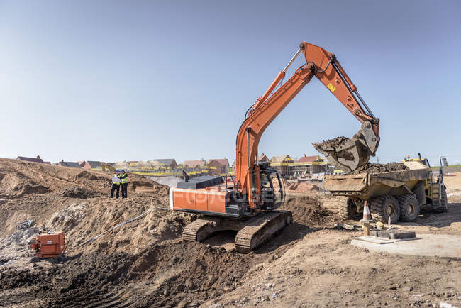 Excavadora moviendo tierra en el sitio de construcción de viviendas - foto de stock