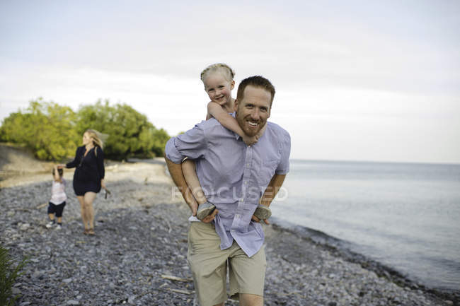 Padre dando a su hija un cerdito en el Lago Ontario, Oshawa, Canadá - foto de stock
