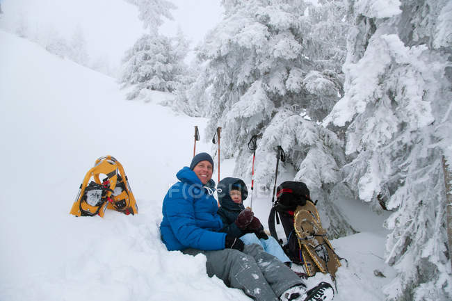 Vater und Sohn ruhen sich beim Schneeschuhwandern aus — Stockfoto