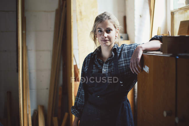 Portrait of young craftswoman leaning on cupboard in organ workshop — Stock Photo