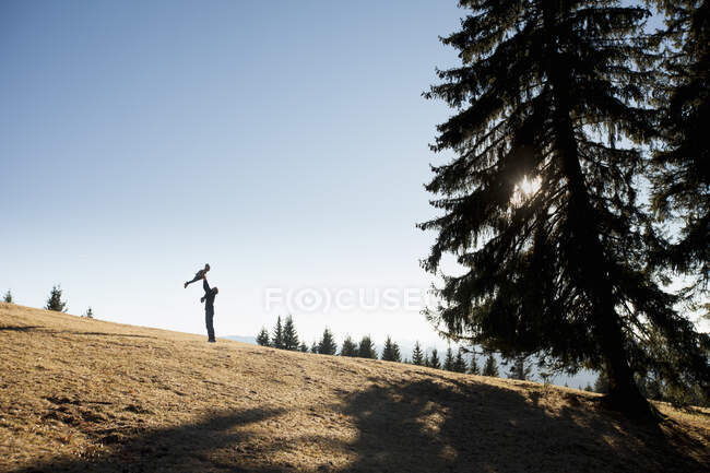 Silhouette dell'uomo che regge la figlia del bambino sulla collina, Tegernsee, Baviera, Germania — Foto stock