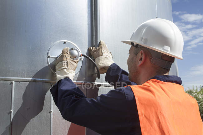 Rear view of technician monitoring pipes outside power station — Stock Photo