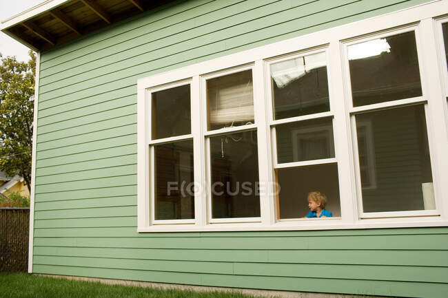 Jeune garçon regardant par la fenêtre — Photo de stock