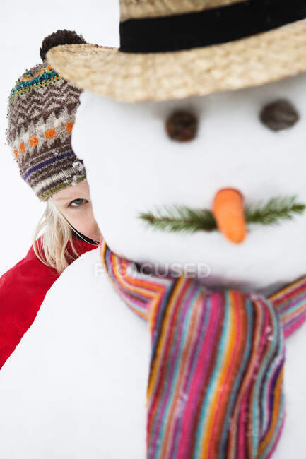 Menina olhando para fora por trás boneco de neve — Fotografia de Stock
