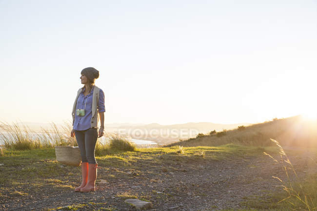 Jovem mulher de pé na colina ao pôr do sol — Fotografia de Stock