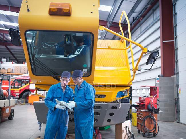 Engineers using digital tablet in truck repair factor — Stock Photo