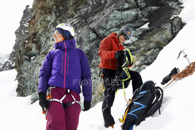 Montañeros preparando equipo en montaña cubierta de nieve, Saas Fee, Suiza - foto de stock