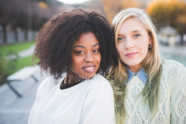 Retrato de dos jóvenes amigas elegantes en el parque junto al lago, Como, Italia - foto de stock