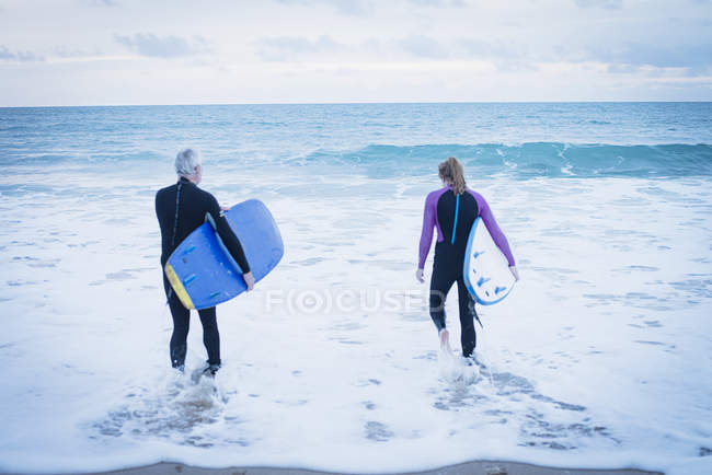 Vater und Tochter gehen mit Surfbrettern ins Meer — Stockfoto