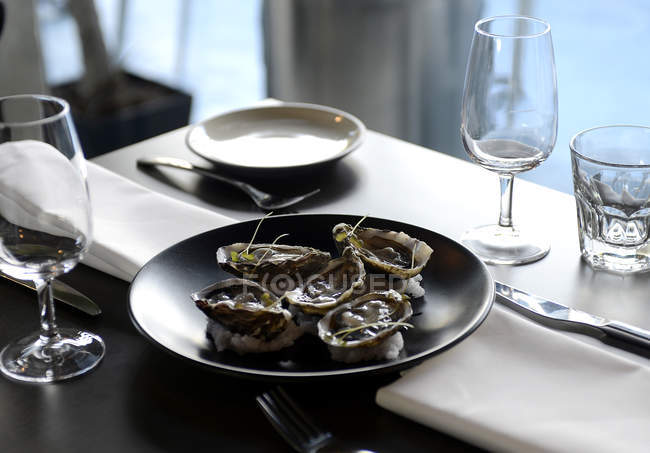 Ostriche servite sul tavolo con bicchieri di vino vuoti — Foto stock
