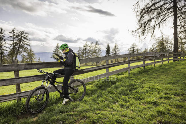 Femme à vélo carte de lecture, Jenesien, Tyrol du Sud, Italie — Photo de stock