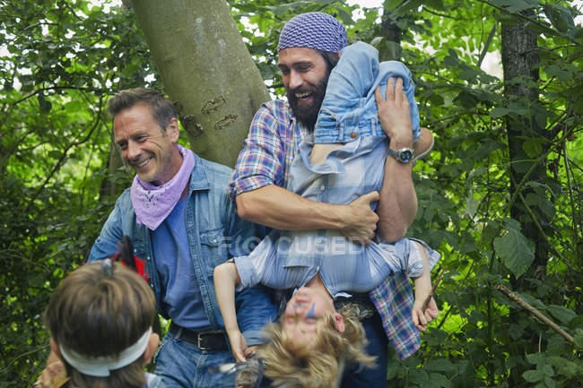 Dois homens adultos e dois meninos vestidos e brincando na floresta — Fotografia de Stock
