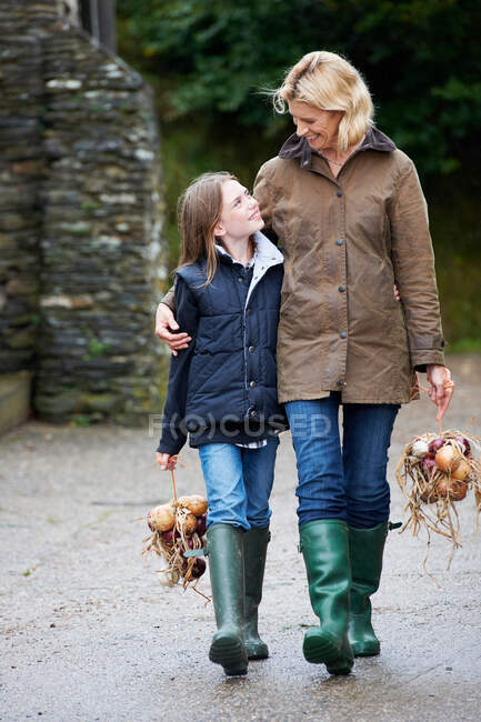 Abuela y niña llevando verduras - foto de stock