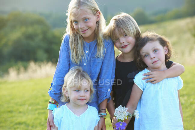 Portrait de quatre frères et sœurs debout dans le champ — Photo de stock