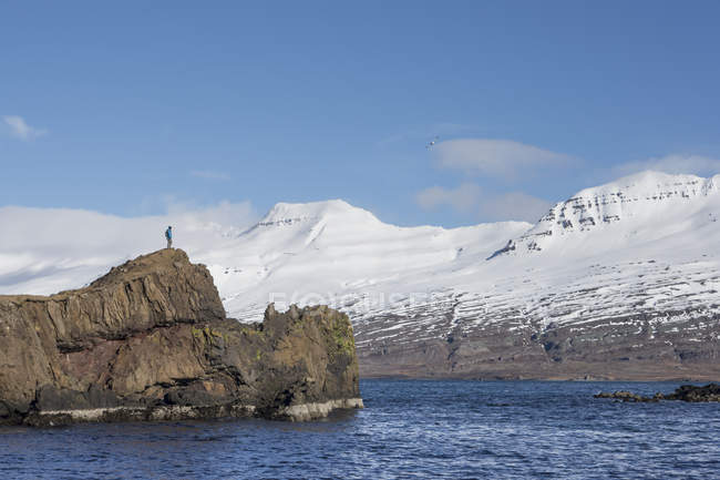 Mann steht am Rande einer kleinen Insel, Island — Stockfoto