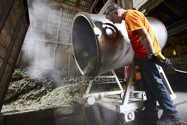 Arbeiter gießt Gemisch aus Bottich in Geschäft — Stockfoto