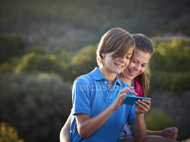 Брат и сестра-подросток с помощью сенсорного экрана в смартфоне, Майя, Испания — стоковое фото