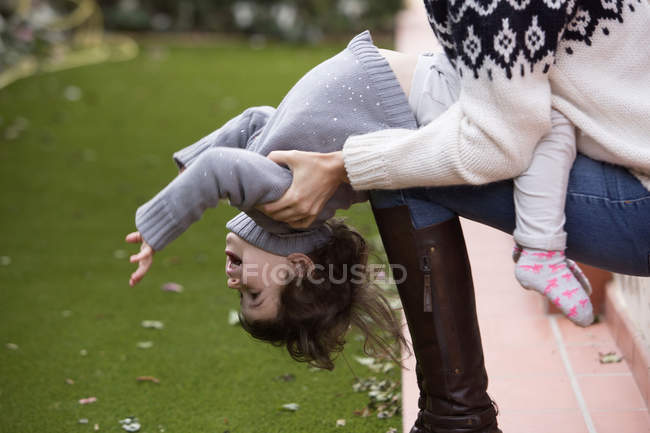 Girl sitting on mothers knee leaning back — Stock Photo