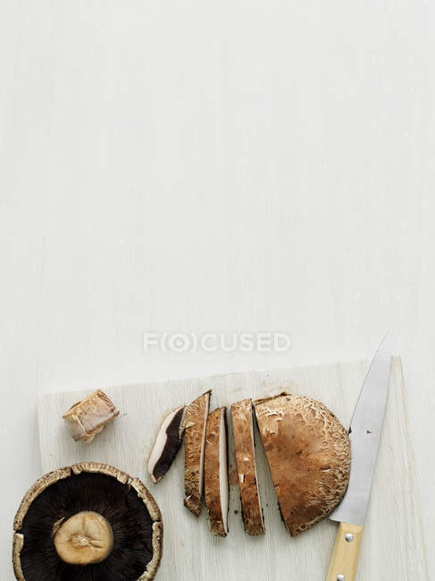 Cogumelos na tábua de corte com faca, vista superior — Fotografia de Stock