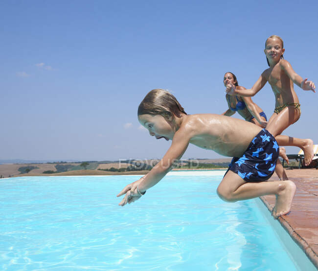 Três pessoas pulando na piscina — Fotografia de Stock
