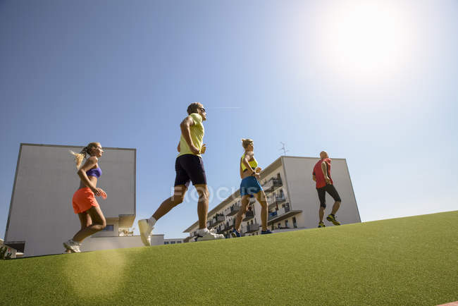 Маленька група людей біжить на траві в місті — стокове фото