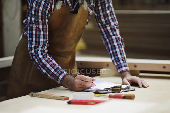 Обрезанный снимок зрелого мастера, делающего заметки в органной мастерской — стоковое фото