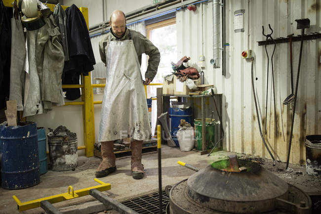 Male foundry worker putting on aluminium coated apron in bronze foundry — Stock Photo