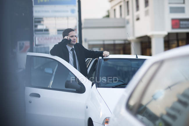 Mid adult businessman chatting on smartphone in city traffic jam — Stock Photo