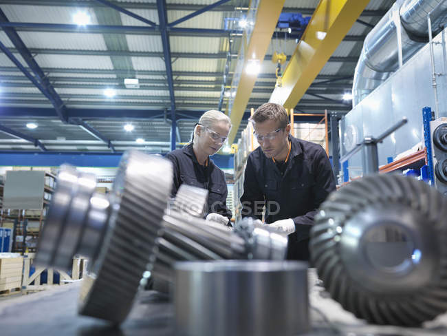 Male and female engineers assembling industrial gearbox in engineering factory — Stock Photo