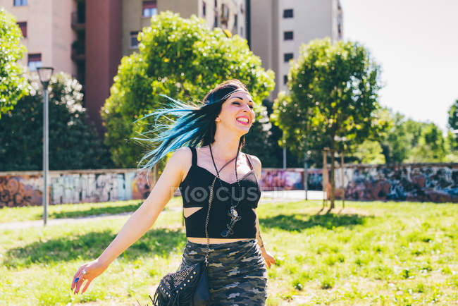 Jeune femme riant et courant dans un parc urbain — Photo de stock