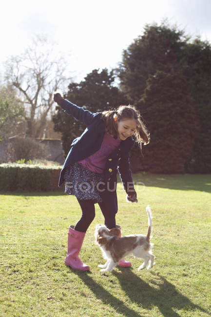Menina brincando no jardim com seu cão de estimação — Fotografia de Stock