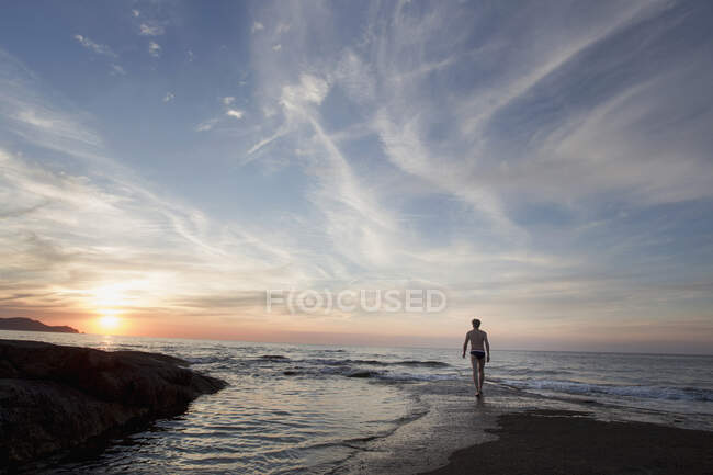 Vista posteriore sagomata dell'uomo maturo sulla spiaggia al tramonto, Calvi, Corsica, Francia — Foto stock