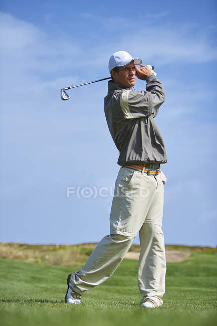 Full length front view of golfer holding golf club taking golf swing — Stock Photo
