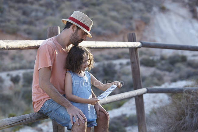 Vater und Tochter sitzen am Zaun und lesen Notizen, Almeria, Andalusien, Spanien — Stockfoto