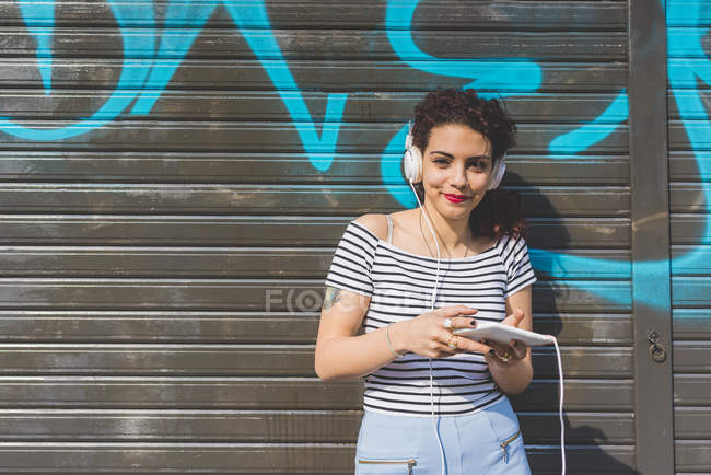 Жінка в навушниках, проведення посміхаючись цифровий планшетний — стокове фото