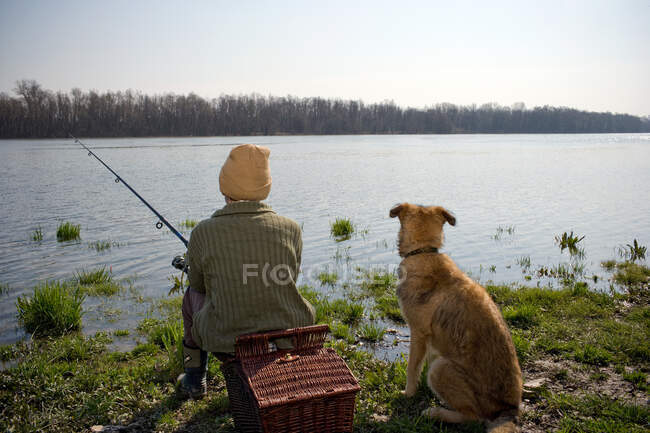 Мальчик рыбачит с собакой — стоковое фото