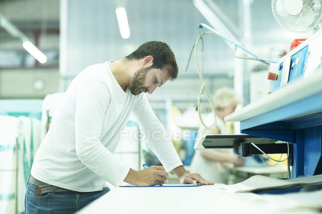 Hombre trabajando en lavanderia tomando notas - foto de stock