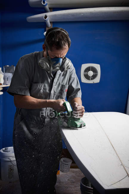 Mitte erwachsener Mann schleift Surfbrett in Werkstatt — Stockfoto