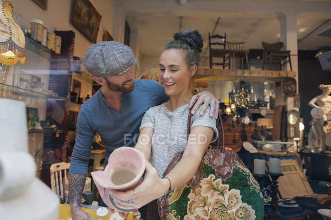 Junge Frau hält rosa Vase in Vintage-Shop — Stockfoto