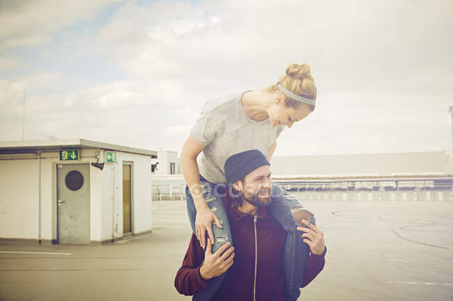 Femme adulte moyenne obtenir tour d'épaule de petit ami sur le toit parking — Photo de stock